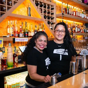 two women standing behind a bar