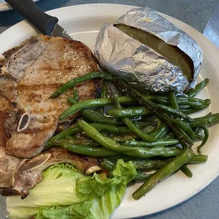 Pork chops cooked to perfection, green beans and a baked potato.