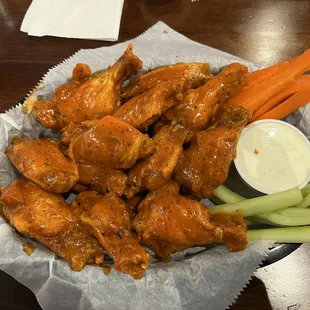 a basket of chicken wings with celery and carrots