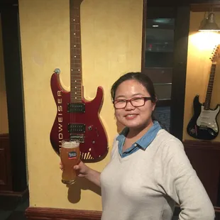 a woman holding a beer and a guitar