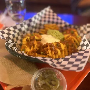 a basket of chili fries and guacamole