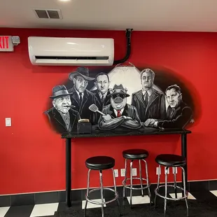 a bar with stools and a painting on the wall
