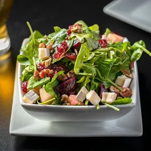 a plate of salad with a fork and glass of beer