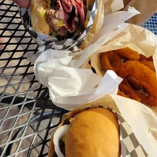 Pastrami burger, onion rings, and cheeseburger