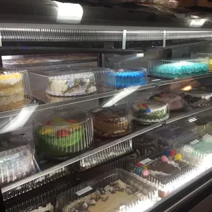 a variety of cakes in a display case