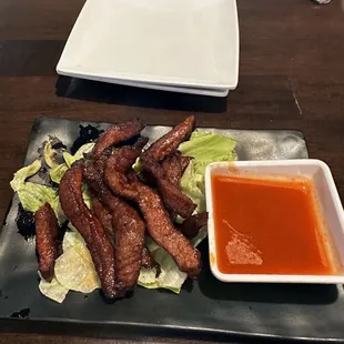 a plate of grilled meat and a bowl of dipping sauce