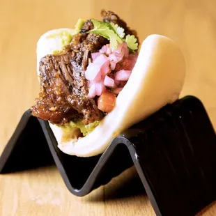 a close up of a bao bun with meat and vegetables