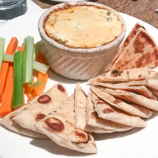 a plate of food with pita chips, carrots and celery
