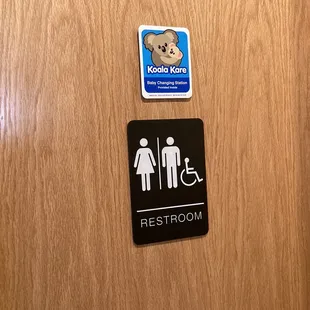 a restroom sign and a teddy bear