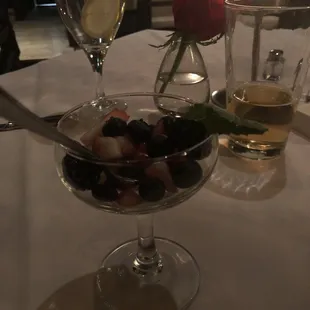 two glasses of wine and a bowl of fruit