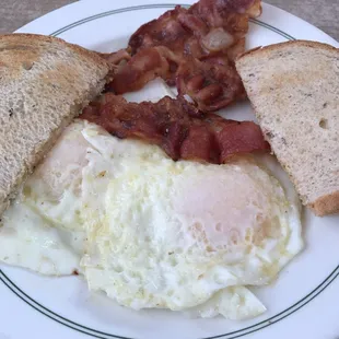 Breakfast treat of eggs, bacon and rye toast.