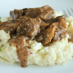 a plate of mashed potatoes with meat and gravy
