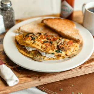 The GOAT! Onions, tomatoes, mushrooms, and spinach cooked into a three egg omelette folded over goat cheese!