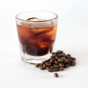 a glass of iced coffee and coffee beans
