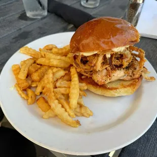 Blackened Chicken on Brioche with fried onion strings and a side of fries.