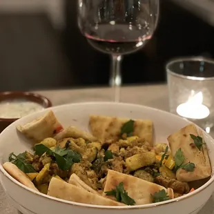 a bowl of food and a glass of wine