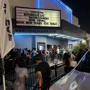 a crowd of people standing outside of a movie theater