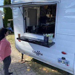 a woman standing in front of a coffee truck