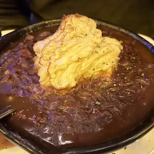 a bowl of stew with a piece of bread