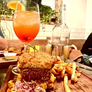 a wooden cutting board with a sandwich and french fries on it