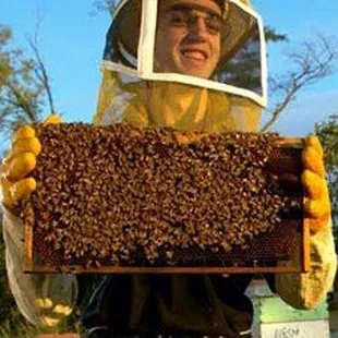 a man in a bee suit holding a beehive