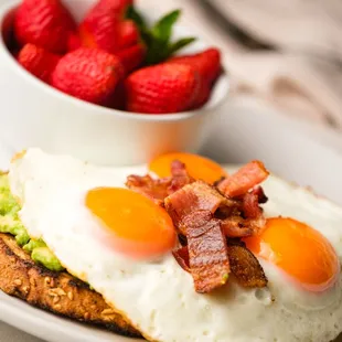 Perfect Avocado Toast: Sourdough toast topped with perfectly ripe avocado mash, 3 eggs done your way, and bacon crumbles.