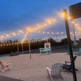 a beach with chairs and string lights