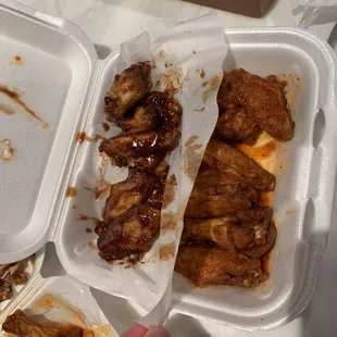 a hand grabbing a piece of food out of a styrofoam container