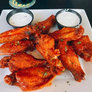 a plate of chicken wings with dipping sauces