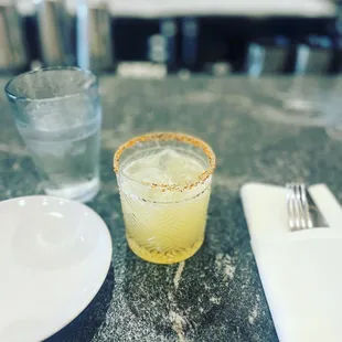 a glass of lemonade next to a plate of silverware