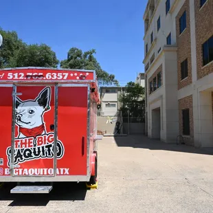 a red food truck parked in front of a building