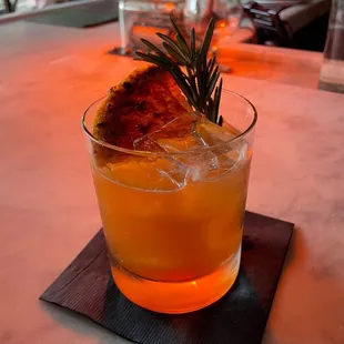 a glass of orange juice with a sprig of rosemary