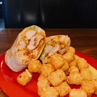 a red plate with a chicken wrap and tater tots