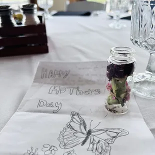 a glass jar with flowers and a butterfly on it