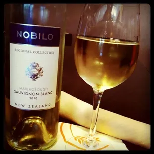 a glass of white wine next to a bottle of wine