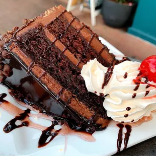 a piece of chocolate cake with whipped cream and a cherry