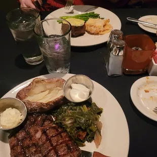 Delmonico with Baked Potato and Collard Greens (Front). Filet with Scalloped Potates and Asparagus (Back).