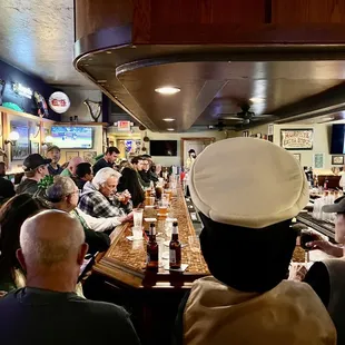 a man in a chef's hat sitting at a bar