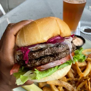 a hand holding a hamburger and fries