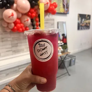 a hand holding a drink in a plastic cup