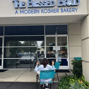 a woman sitting in a chair in front of a bakery