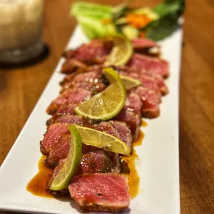 a plate of steak with lime slices