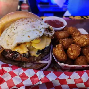 The works burger with an egg and tater tots