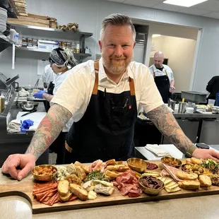 a man standing behind a board of food