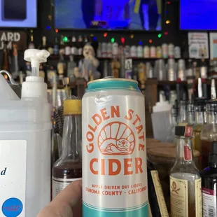 a person holding a can of cider