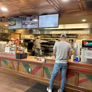 a man standing at a counter in a restaurant