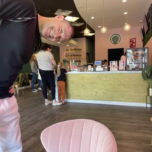 a man standing in front of a pink chair