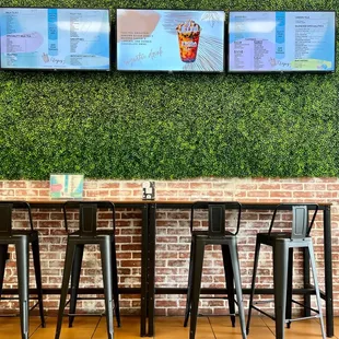 a row of bar stools in front of a brick wall