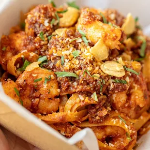 a hand holding a container of pasta