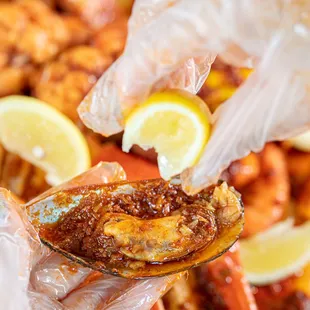 a hand holding a spoon full of fried fish